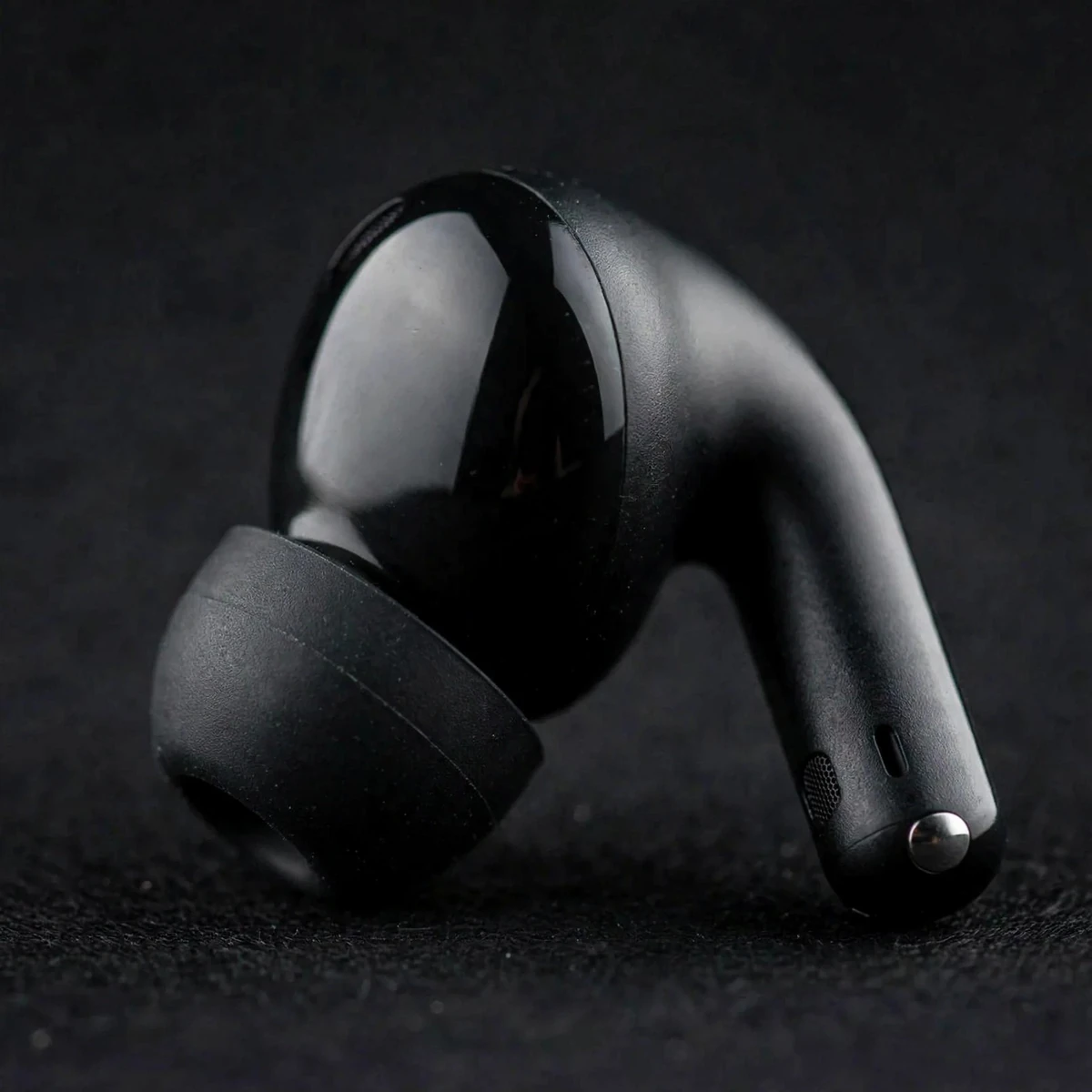 Extreme macro of one black Xiaomi Redmi Buds 5C earbud: glossy round touch face, curved stem and silicone eartip
