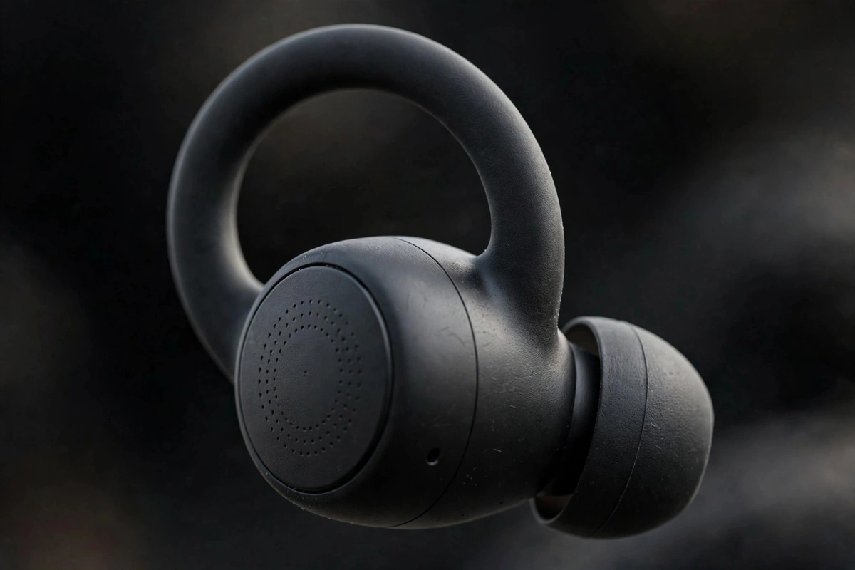 Macro of a black Valdus VTS-220 hang-ear earbud showing the ear hook and touch panel