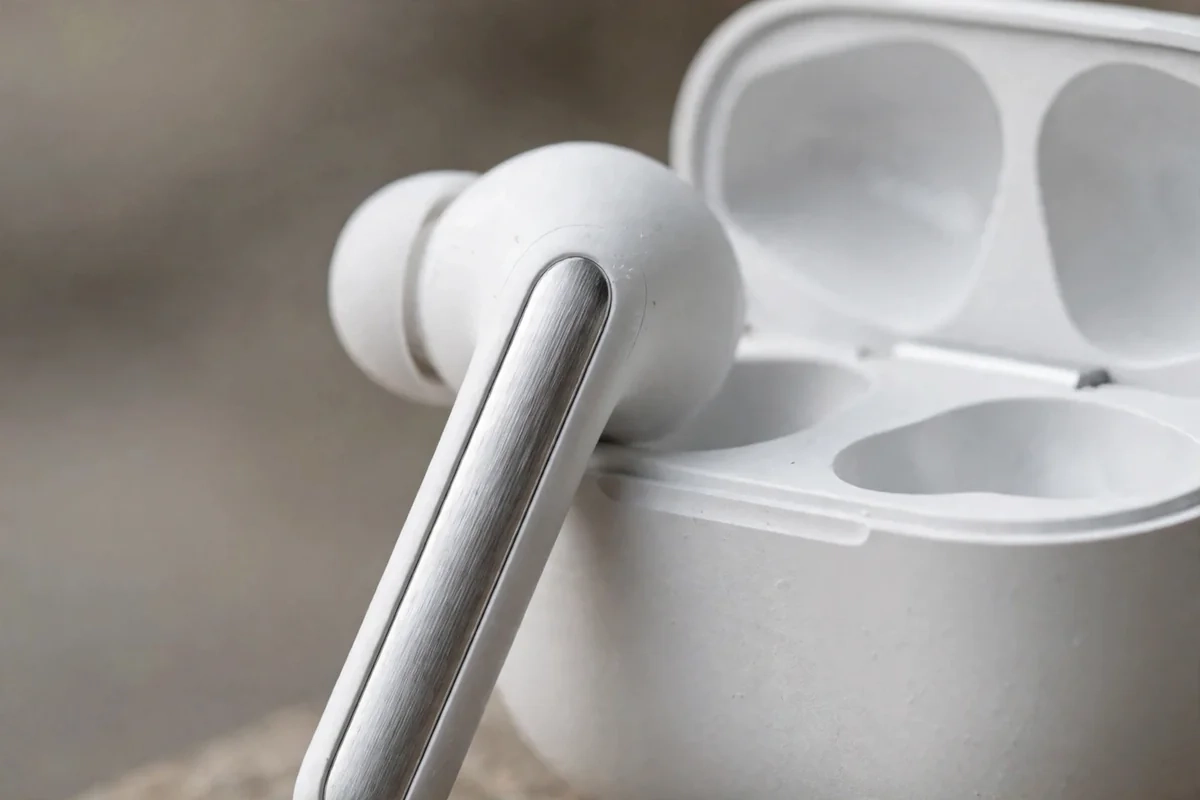 Close-up of Valdus VNC-350 earbuds showing metallic electroplated stems and the case's cyan LED strip