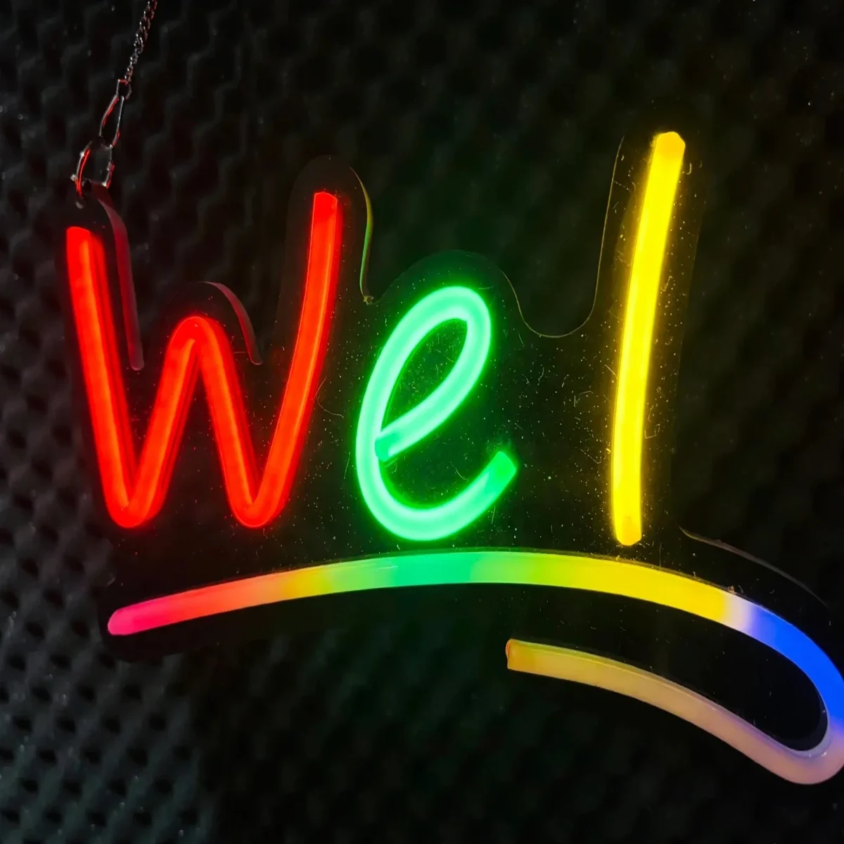 Close-up of the glowing red, green, and yellow letters on the GearUP WELCOME neon sign
