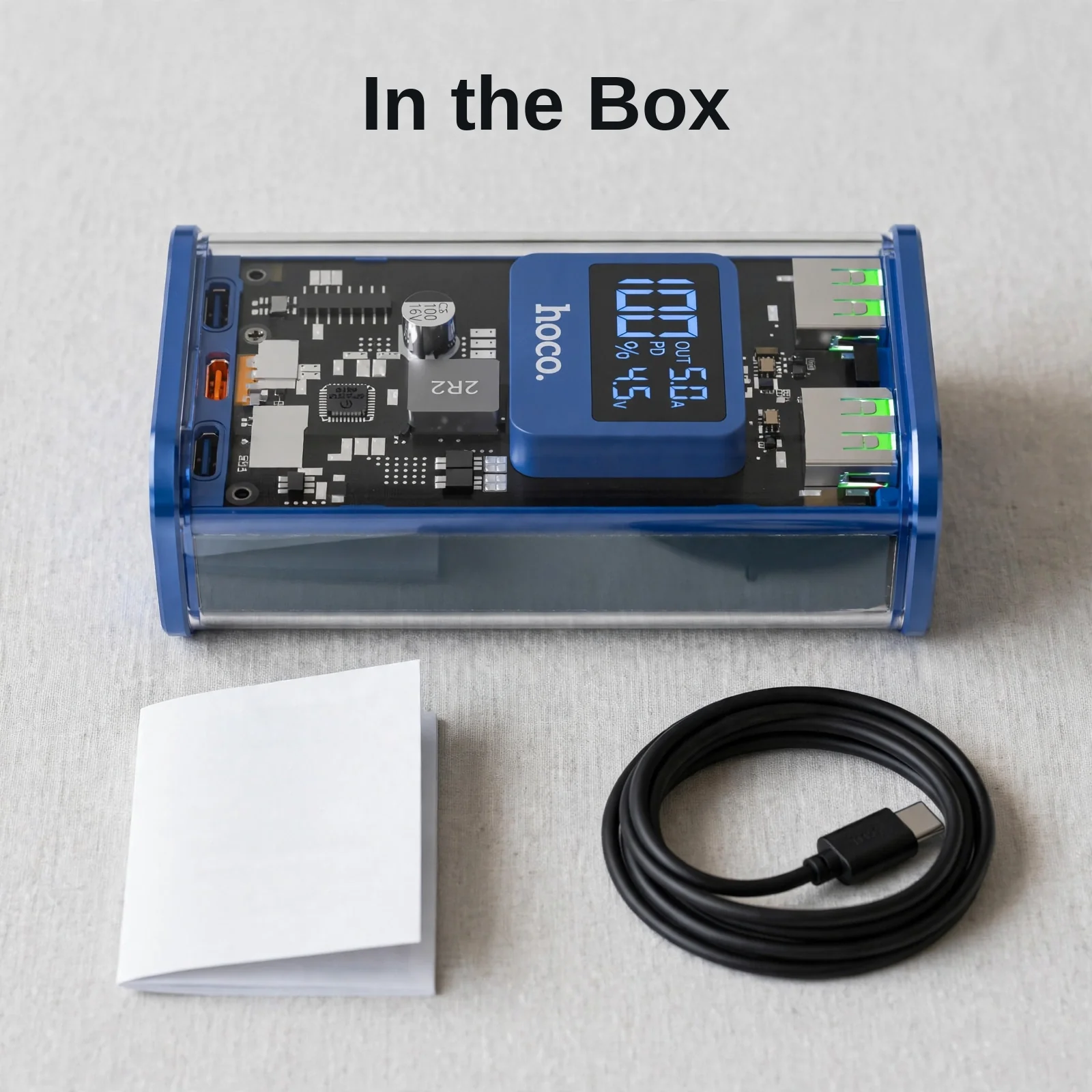 Hoco J105 in the box: blue power bank, charging cable and user manual laid out on a table