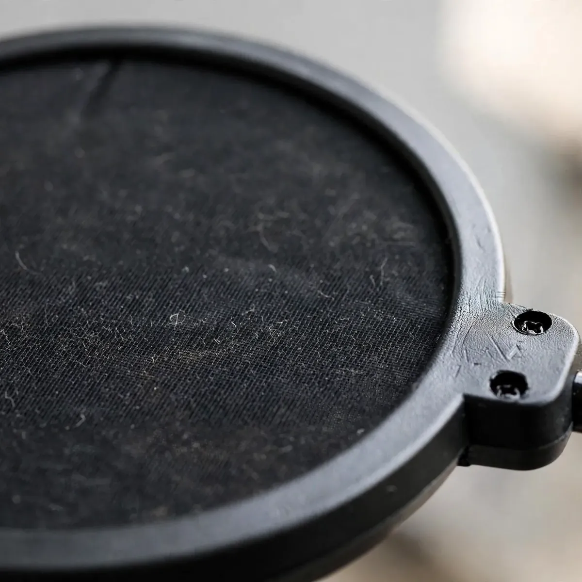 Wind pop filter mesh macro — close-up of the dual-layer mesh screen, no text.
