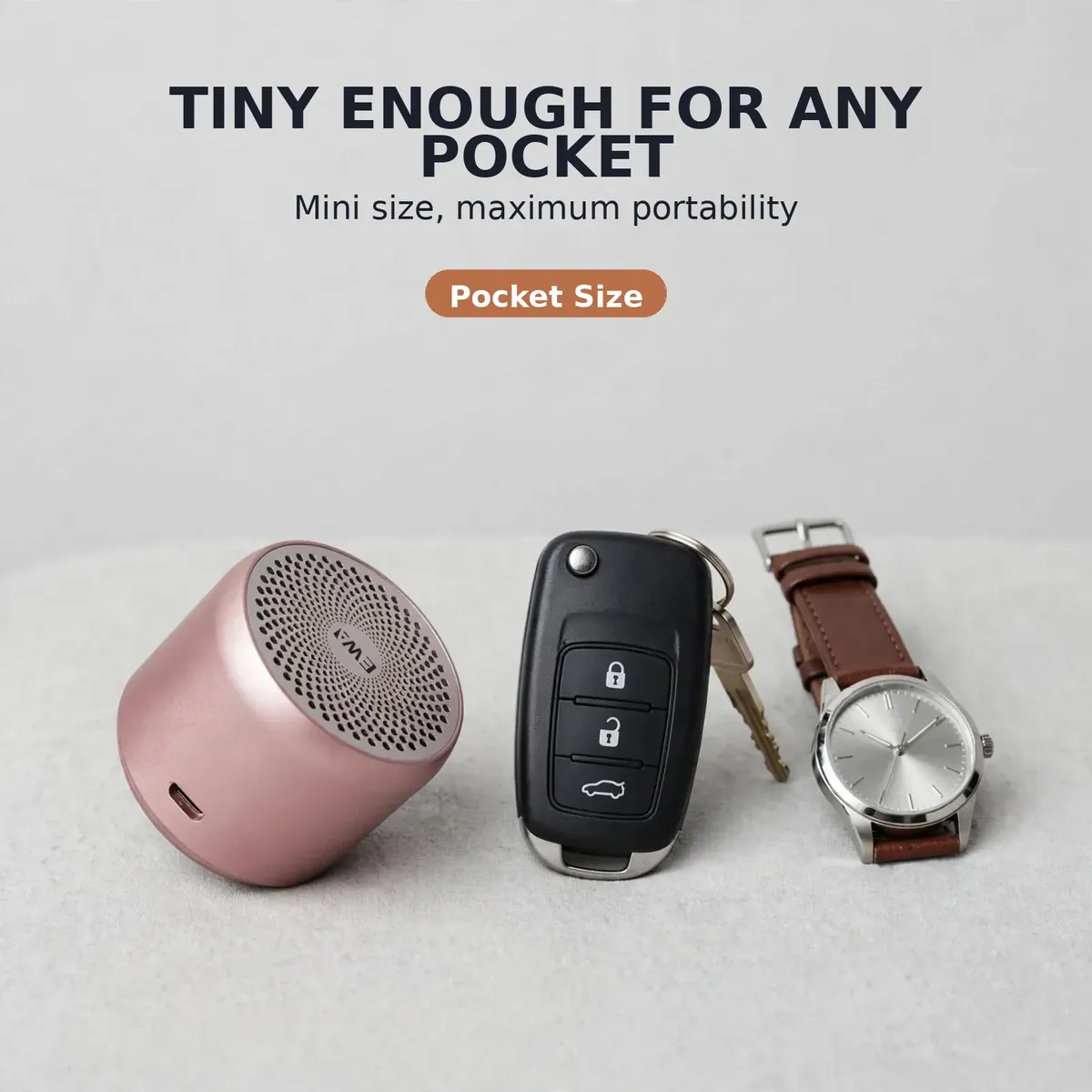 Ewa A106 Pro pocket size card showing the rose gold speaker beside a car key fob and wristwatch for scale