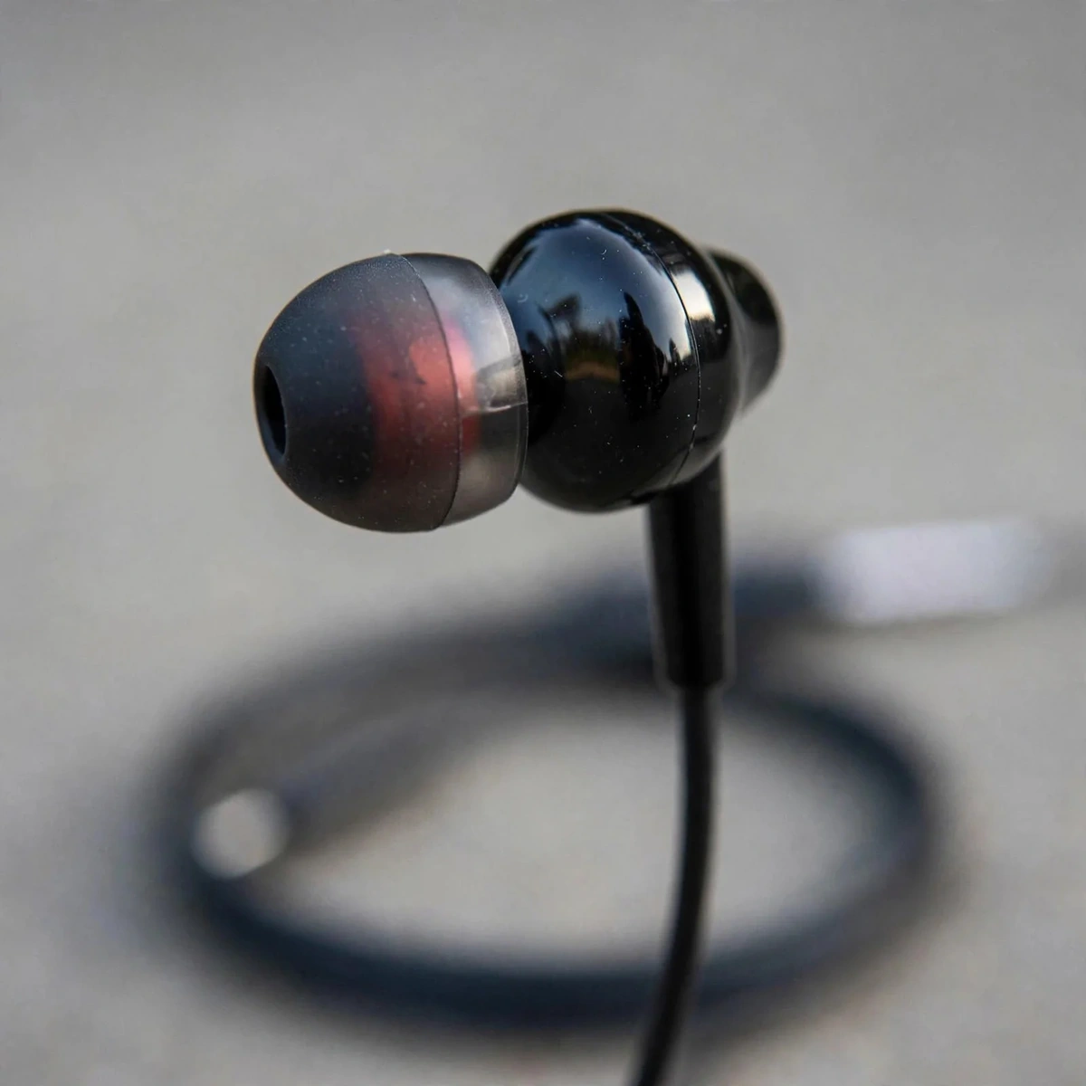 Close-up of the black Geeoo X10 in-ear earbud with red driver accent visible through the shell