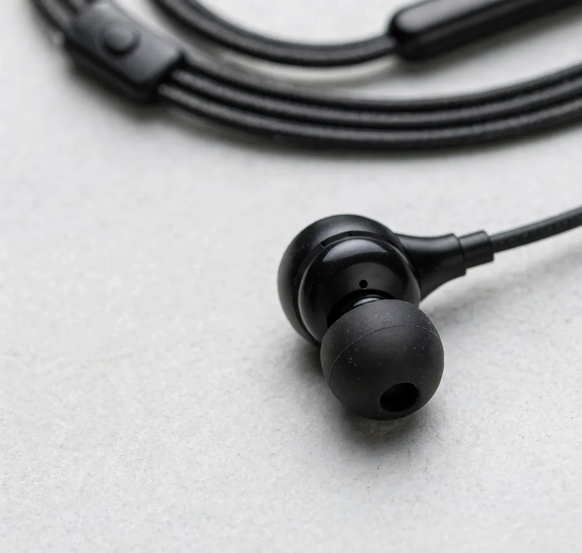 Close-up of the black Hoco M116 in-ear earbud with silicone tip