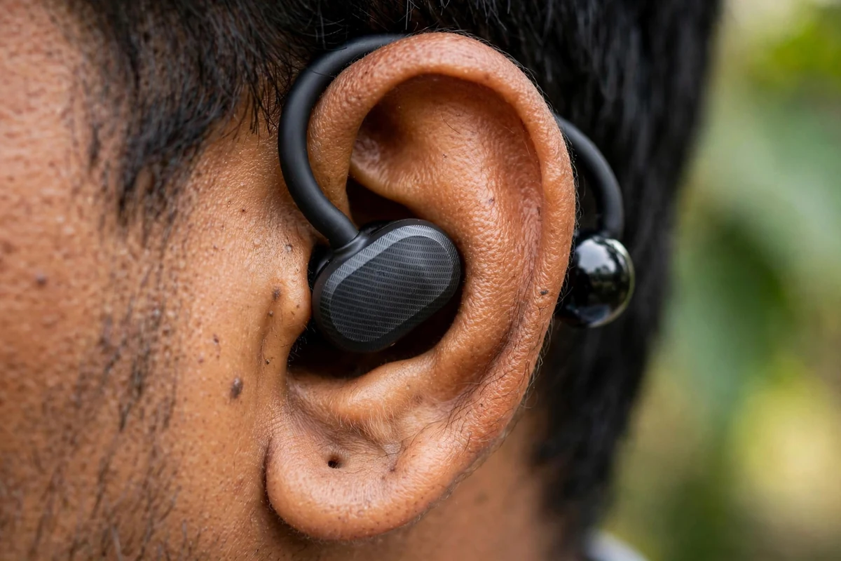 Close-up of a SoundPEATS Air Clip earbud clipped on the ear — speaker capsule in front of the canal, arch over the ear, canal visibly open