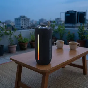 Awei Y788 Bluetooth speaker with its RGB lights on, standing on a rooftop table at dusk